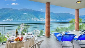Un balcone con un tavolo apparecchiato per mangiare, una sedia e una poltrona blu.