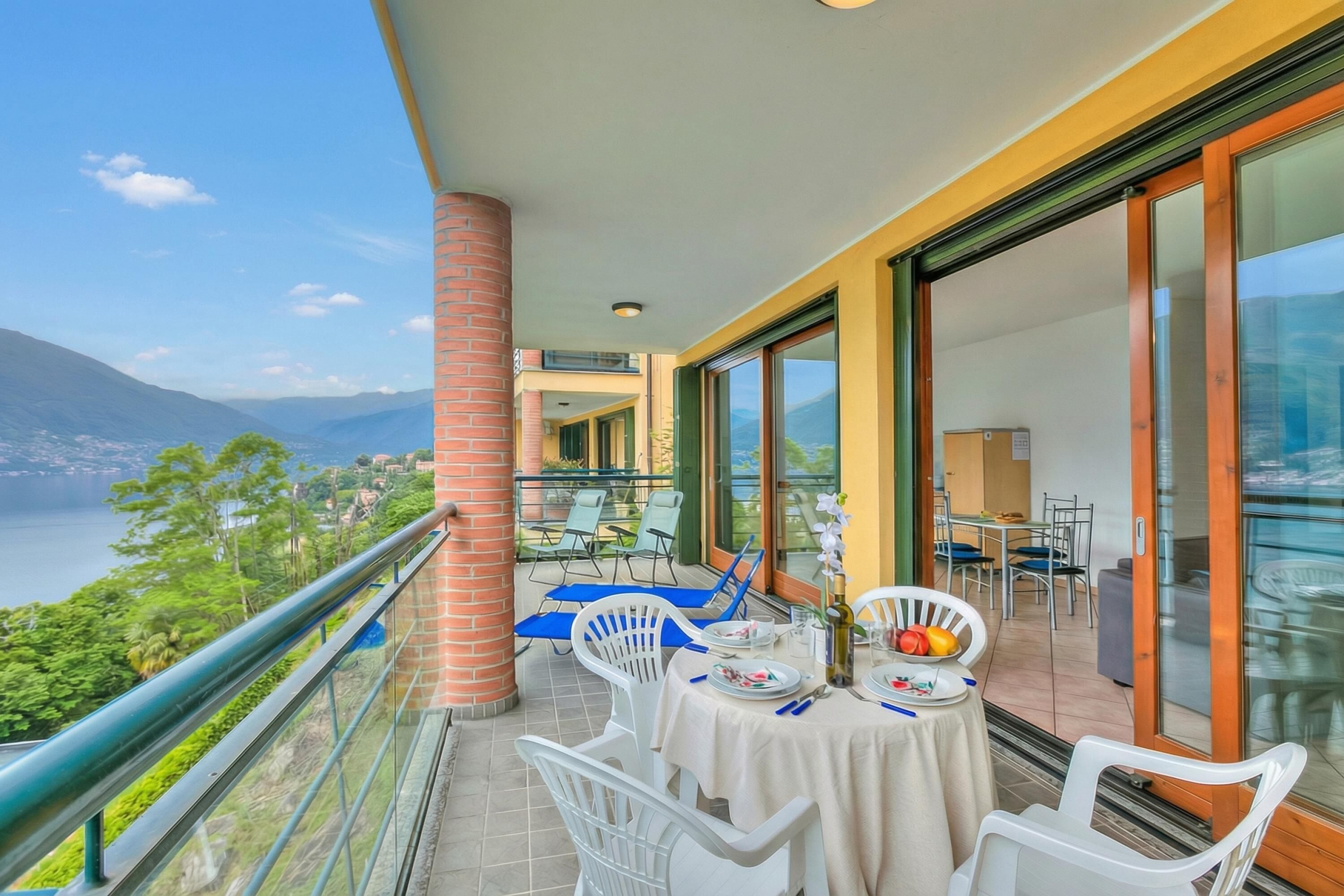 A balcony with a table set for dining, overlooking a mountainous landscape.