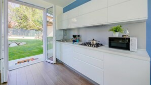 A modern kitchen with a sliding glass door leading to a backyard, a built-in microwave, and a gas stove. - Villa Il Gelsomino Bellavista (Besozzo)