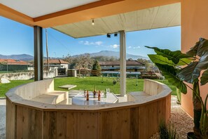 Una zona de bar con barra de madera y vistas a un jardín con césped y montañas.