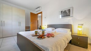 A modern bedroom with a bed, bedside tables, a wardrobe, and a framed picture on the wall.