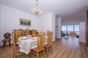 A dining area with a table set for four, wooden chairs, a chandelier, and a painting on the wall.