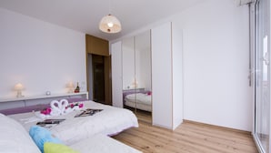 Quarto moderno com duas camas, um guarda-roupa e uma mesa de cabeceira com abajures.