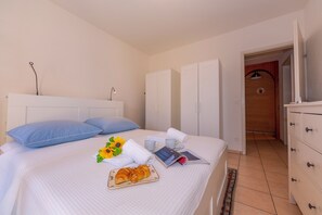 A neatly made bed with a tray of croissants, a book, and a cup of coffee. - Casa Bader (Riva San Vitale)