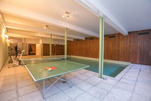 A ping pong table in a room with a wooden wall and a tiled floor. - Casa Bader (Riva San Vitale)
