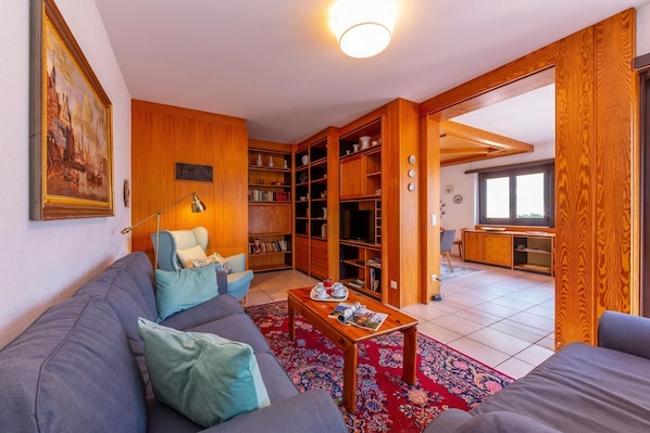 A living room with a sofa, coffee table, and bookshelves. - Casa Bader (Riva San Vitale)