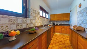 Una cocina con armarios de madera, salpicadero de azulejos y frutero en la encimera.