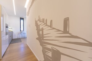 Stylish hallway leads to a kitchen with white cabinetry and a dining area.