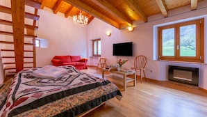 A bedroom with a bed, a TV, a fireplace, and a large window. - Casa Gialla (Arogno)