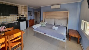 Ein Schlafzimmer mit einem Bett, einem hölzernen Kopfteil, einem Nachttisch und einem kleinen Holzschemel.
