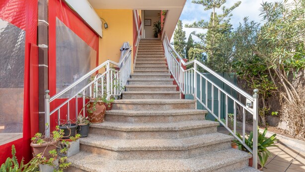 Eine Treppe mit Geländer, die zu einer Tür oben führt.