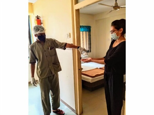 A hotel room with a bed, a bedside table, and a window with curtains. - Hotel Vaishali (Nashik)