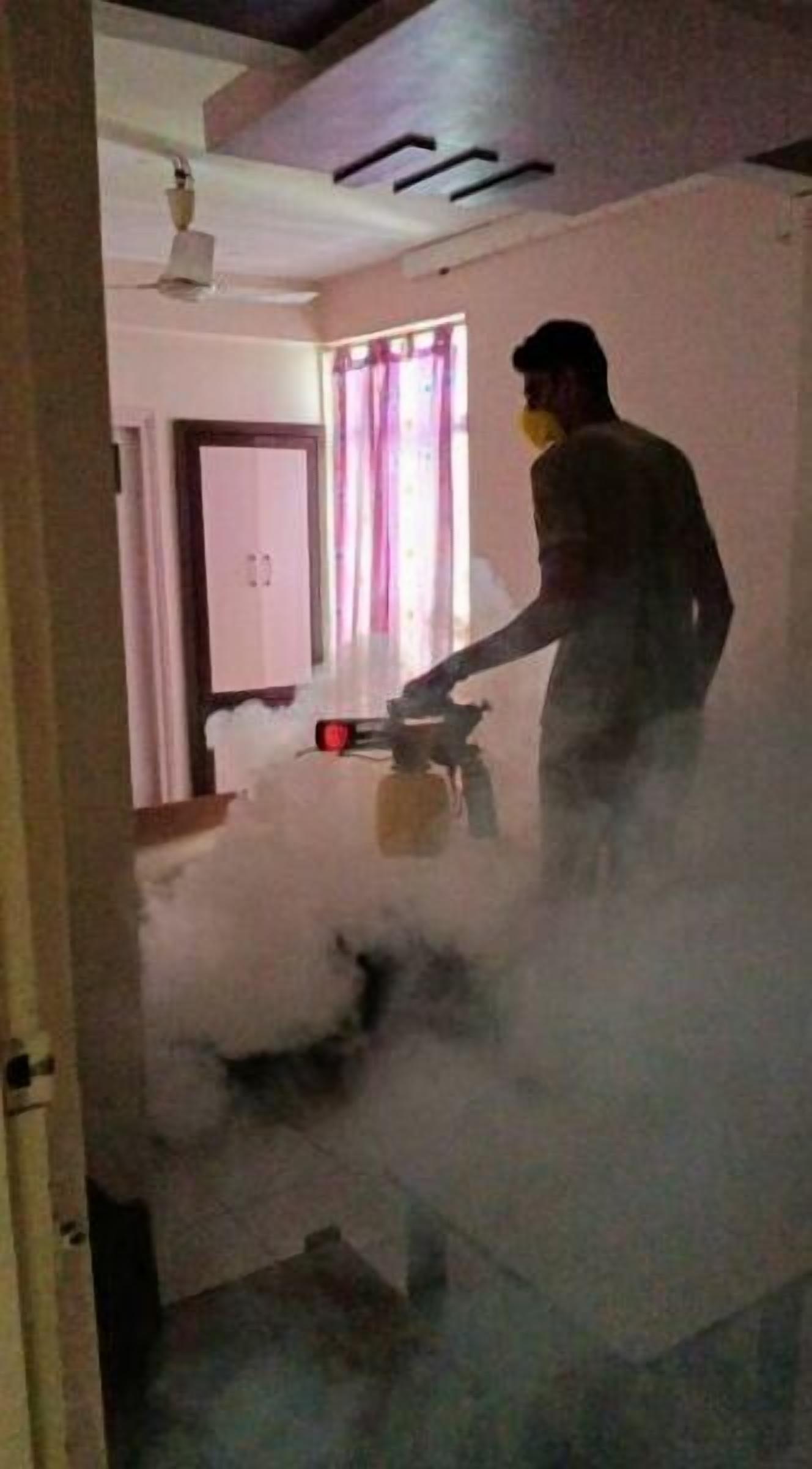 A person using a vacuum cleaner in a room with a door, a window with curtains, and a ceiling fan.