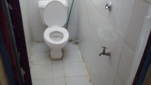 A small, narrow bathroom with a toilet, a visible pipe, and a wall-mounted faucet. - Jackmart Lodge - Adults Only (Nakuru)