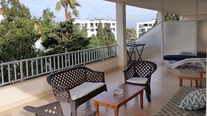 A balcony with wicker furniture, a wooden table, and a sofa. - Central Apartment "Portosun Caracol" Close to the Beach (portocolom)