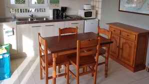 A kitchen with wooden cabinets, a dining table with chairs, a coffee maker, a microwave, and a map on the wall. - Central Apartment "Portosun Caracol" Close to the Beach (portocolom)