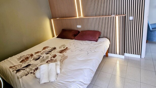 A modern bedroom with a bed, pillows, and a wooden slatted headboard. - Central Apartment "Portosun Caracol" Close to the Beach (portocolom)