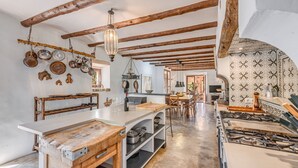 A rustic kitchen with exposed wooden beams, a central island with a sink, and a patterned backsplash. - Mediterranean country house with Wi-Fi, Pool and Garden (Cala Mondrago)