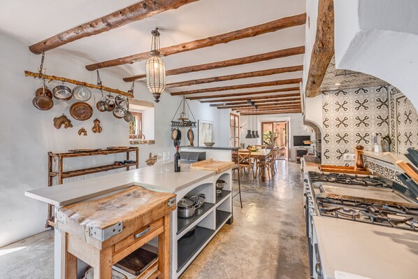 A rustic kitchen with exposed wooden beams, a central island with a sink, and a patterned backsplash. - Mediterranean country house with Wi-Fi, Pool and Garden (Cala Mondrago)