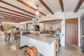 Une cuisine spacieuse avec des poutres en bois, un îlot central et une grande porte en bois.