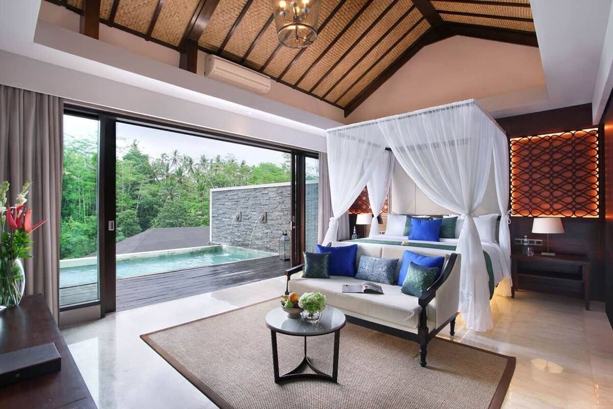 A modern bedroom with a large window, a bed with white and blue bedding, and a view of a swimming pool.