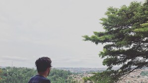 A person standing on a balcony overlooking a cityscape with greenery and buildings. - Choose Kigali (Kigali)
