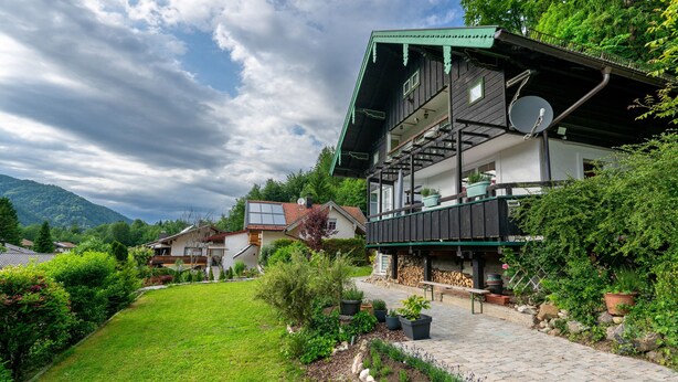 Une maison à deux étages avec un balcon, une antenne parabolique et des plantes en pot.