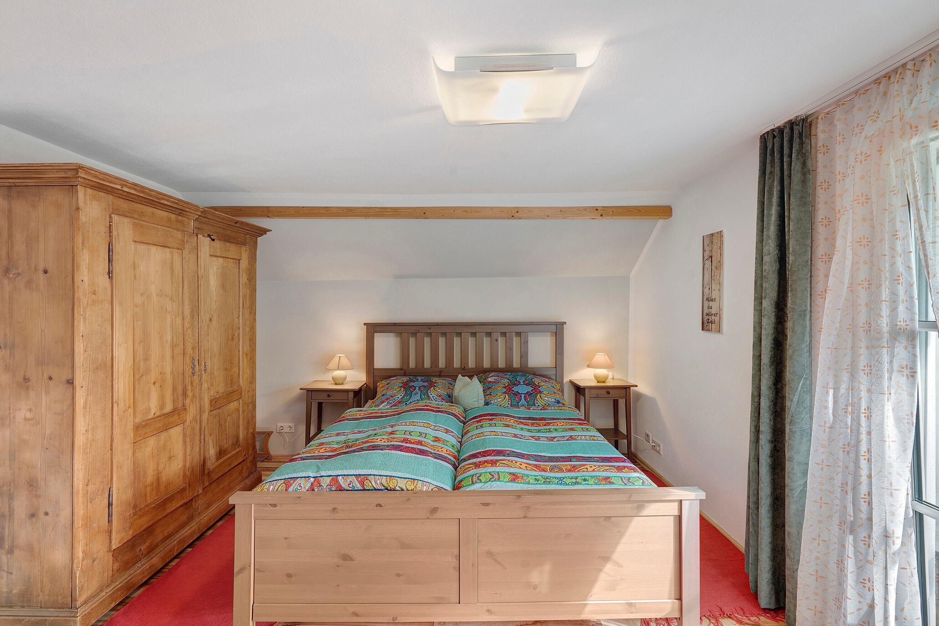 Una camera da letto con un letto di legno, due comodini con lampade, un armadio e una finestra con tende.