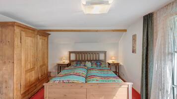 Una camera da letto con un letto di legno, due comodini con lampade, un armadio e una finestra con tende.