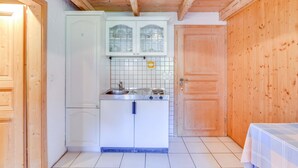 Una cocina compacta con estufa, lavabo y alacenas, paredes de madera y piso de baldosas.
