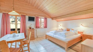Una habitación de madera con cama, escritorio, silla y mesa.