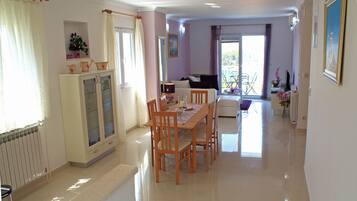 Amplia sala de estar con una mesa de comedor, sillas, un sofá y un balcón con vistas.
