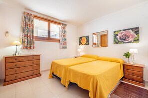 Ein Zimmer mit zwei Betten, einem Schminktisch, einem Spiegel und zwei Bildern.