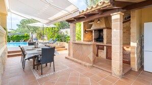 Une terrasse extérieure avec une piscine, un espace barbecue et un coin repas.