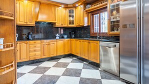 Une cuisine avec des meubles en bois, un réfrigérateur en acier inoxydable et un carrelage à carreaux.