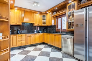 A kitchen with wooden cabinets, a stainless steel refrigerator, and a checkered floor.