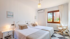 Une chambre d’hôtel avec deux lits, une table de chevet, une chaise, une fenêtre donnant sur un beau paysage et un luminaire au plafond.