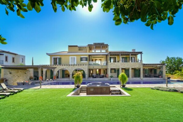 A large, two-story building with a swimming pool, outdoor seating, and a well-maintained lawn.