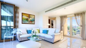 A modern living room with a white sofa, a glass coffee table, and a clear chair. - Villa 141 - Rio (Kouklia)