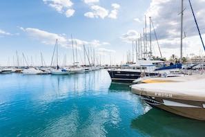 A marina with multiple boats docked, calm water, and a clear sky.