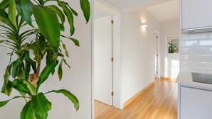 Un interior moderno con piso de madera, paredes blancas y una planta verde grande.