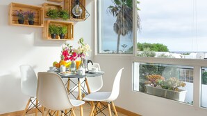 Comedor con mesa, sillas y plantas en macetas sobre estantes.