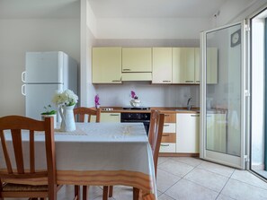 A kitchen with a dining table, chairs, a refrigerator, and cabinets.