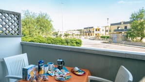 Un balcón con una mesa dispuesta para el desayuno, incluyendo una caja de galletas, una cafetera y diversos productos para el desayuno.