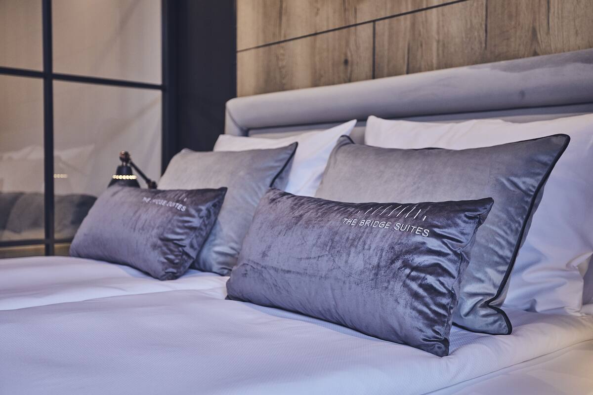 A bed with grey pillows and a wooden headboard.
