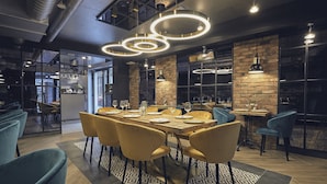 Una sala da pranzo moderna con un lungo tavolo in legno, sedie gialle e un tappeto decorato.