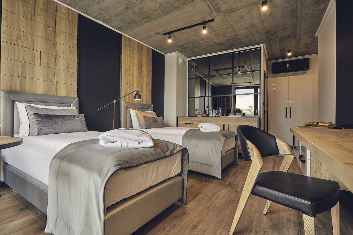 A modern hotel room with a large bed, a desk, and a chair.