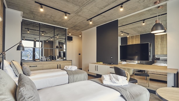 Una moderna camera d'albergo con un letto grande, una scrivania, una TV e vista sulla città.