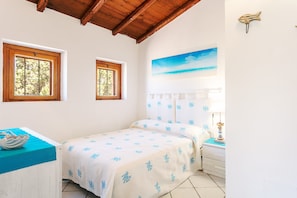 Une chambre à coucher avec un lit, deux fenêtres, un tableau, une table de chevet et une lampe.