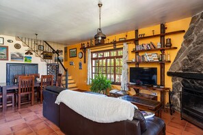 Un salon avec une cheminée, un téléviseur et un escalier.